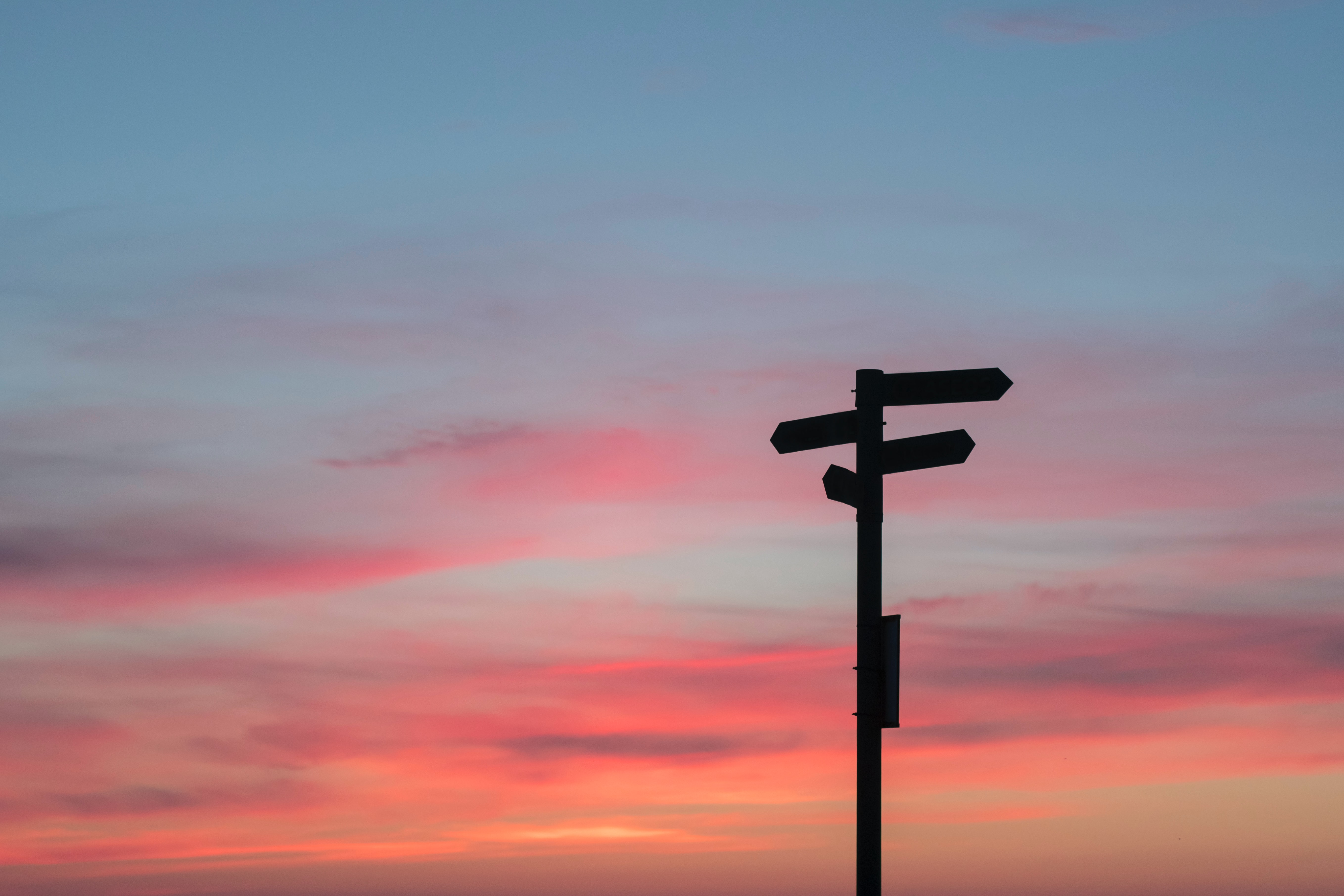 silouette of a sign on a road with the sun setting in the background.